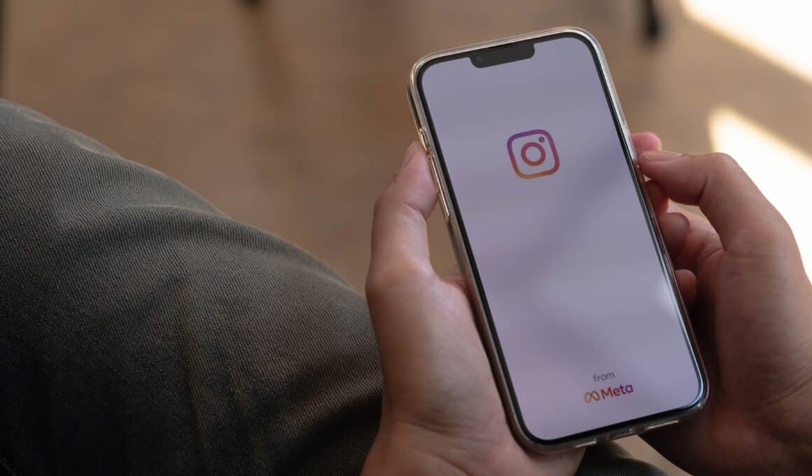 Mão segurando um iPhone com o Instagram abrindo