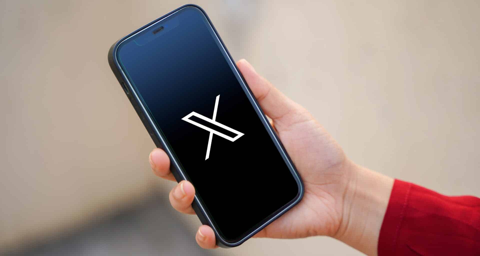 Mão segurando um iPhone com o logo do X