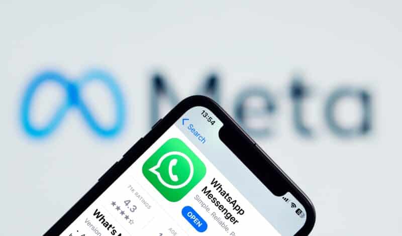 WhatsApp na App Store, em um iPhone, com o logo da Meta ao fundo