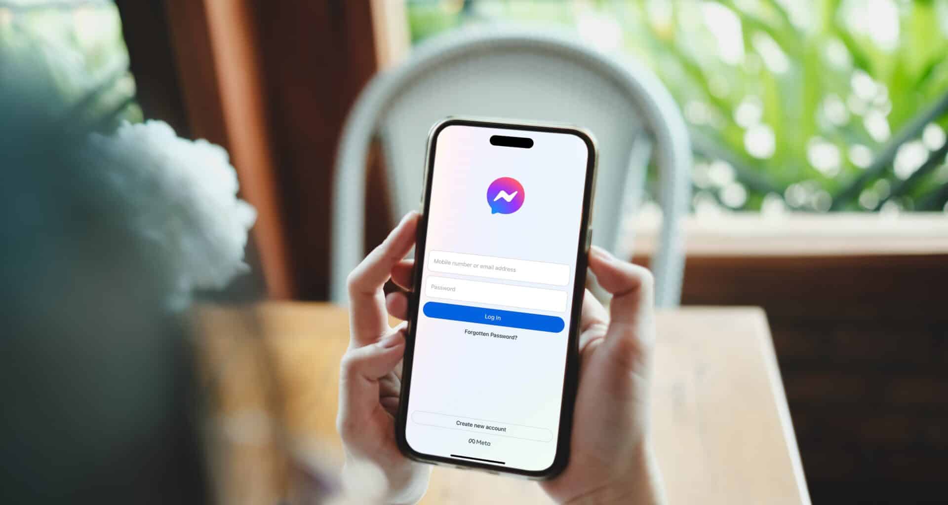 Mão segurando um iPhone rodando o Messenger