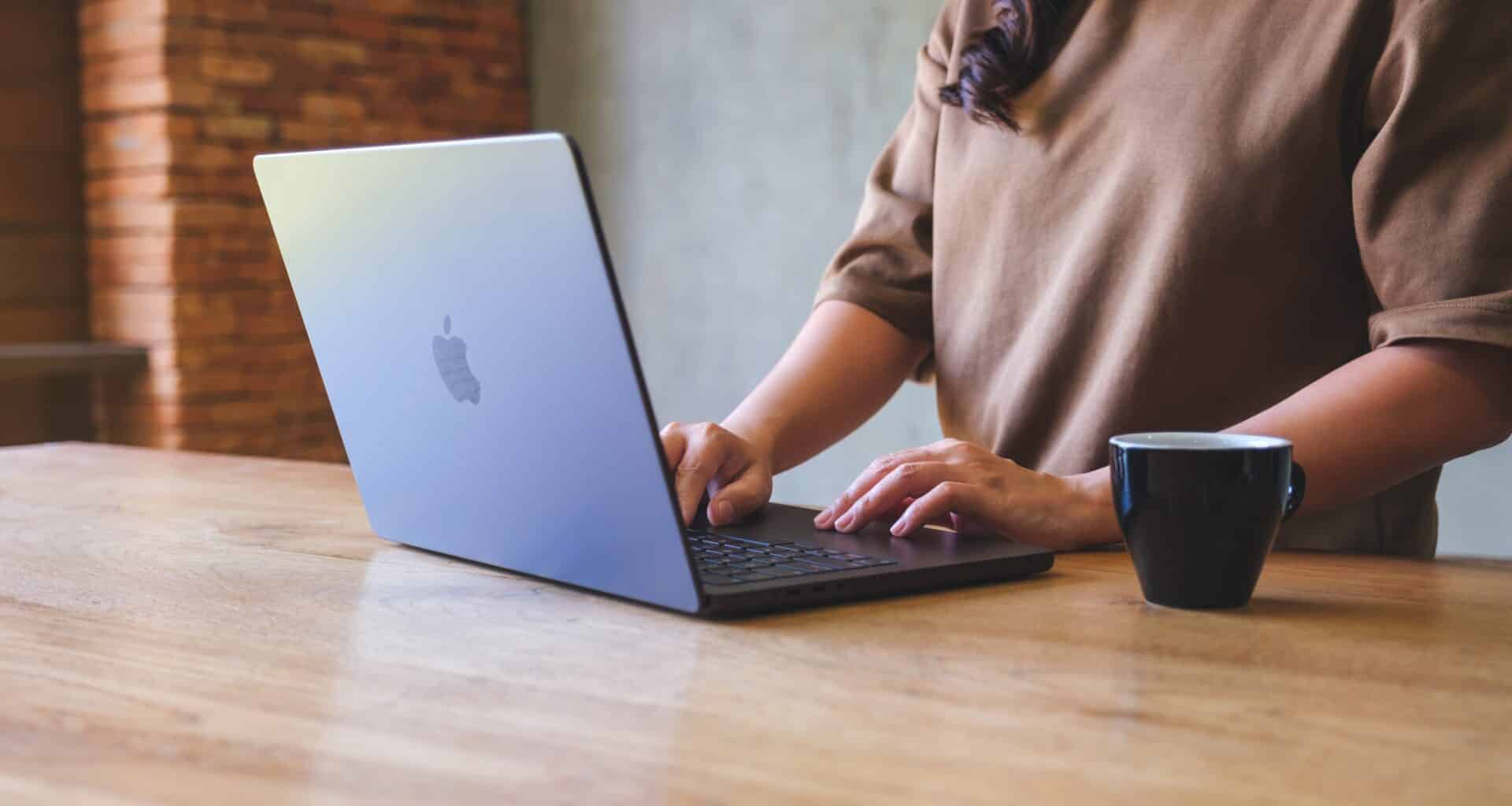 Mulher trabalhando num MacBook Pro com café ao lado