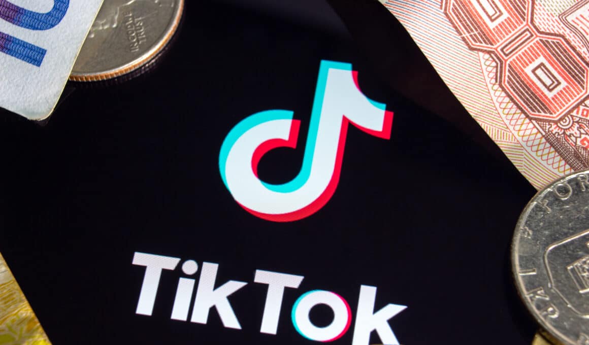 Logo do TikTok cercado por notas de dinheiro