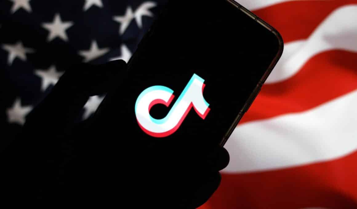 Logo do TikTok em um smartphone frente à bandeira dos Estados Unidos
