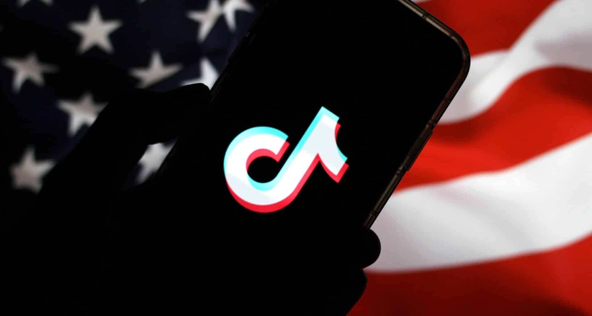 Logo do TikTok em um smartphone frente à bandeira dos Estados Unidos