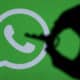 Mão segurando uma chave com o logo do WhatsApp ao fundo