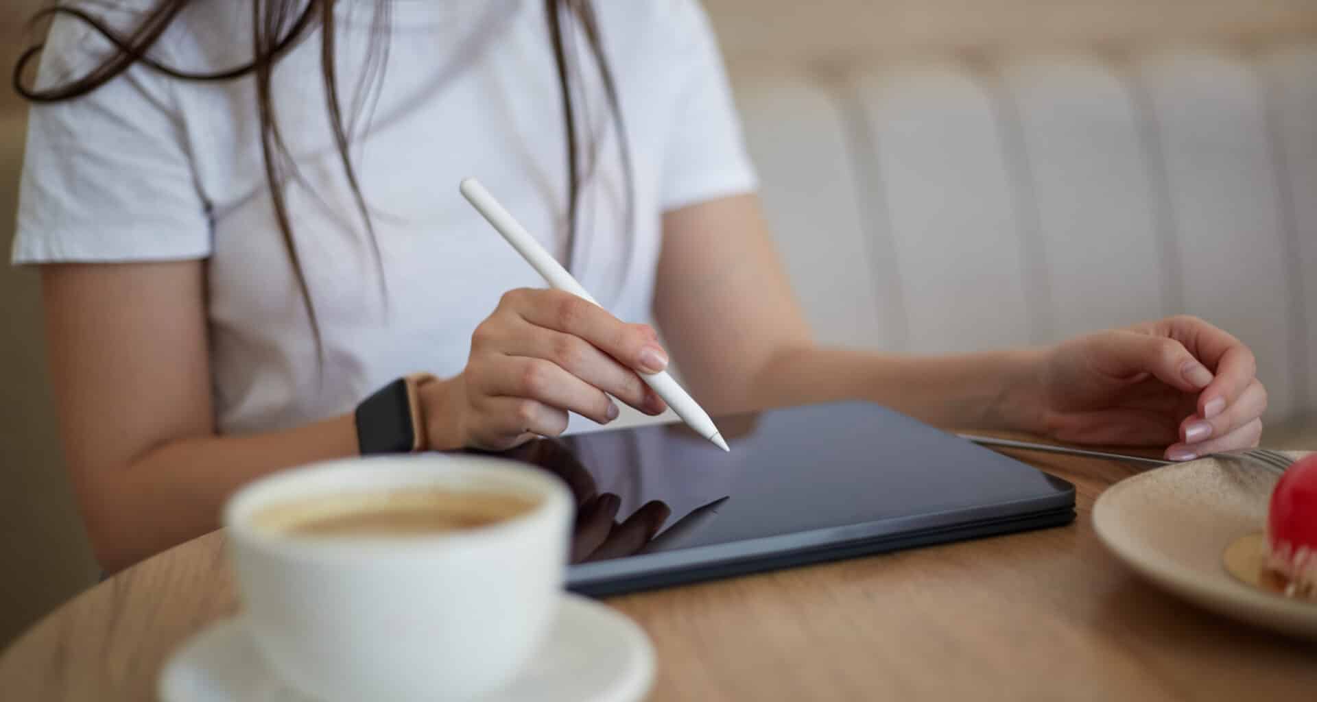 Mulher trabalhando com Apple Pencil num iPad em café