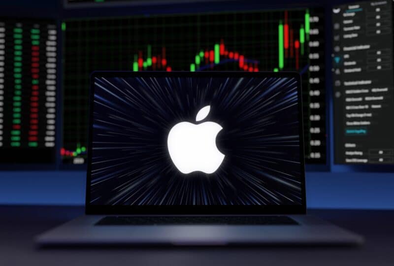 Logo da Apple em frente a tela com negociações de ações