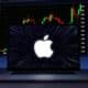 Logo da Apple em frente a tela com negociações de ações