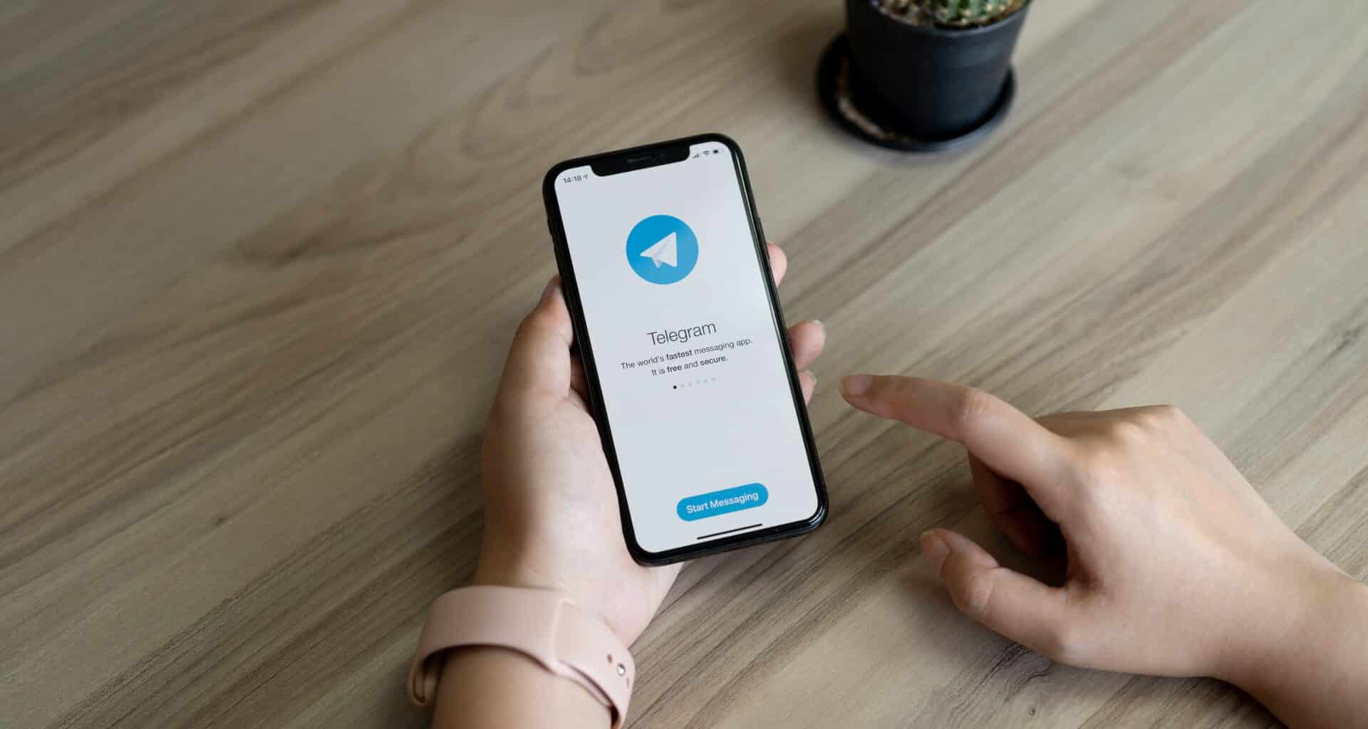 Mão segurando um iPhone com o app Telegram