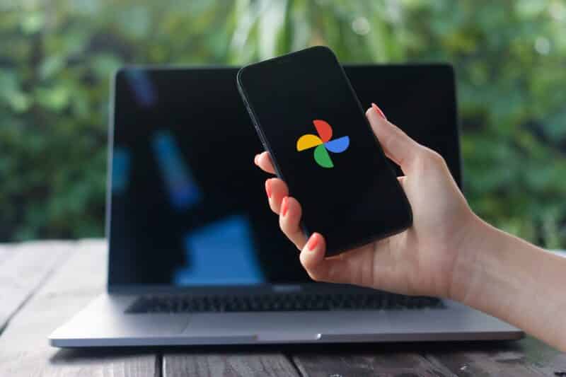 Logo do Google Fotos em um iPhone em frente a um MacBook