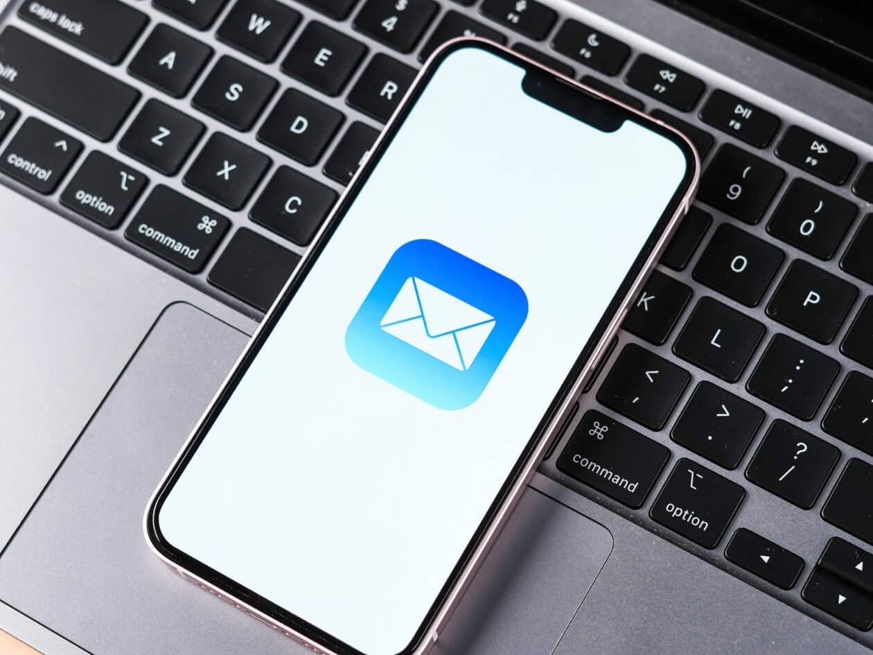 Ícone do app Mail no iPhone em cima de um Mac