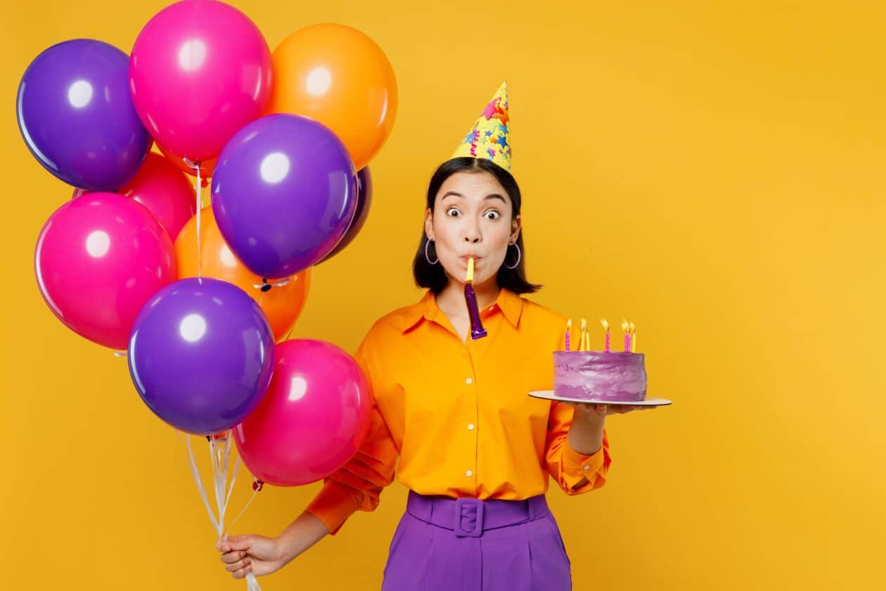 Mulher segurando balões e bolo para comemorar aniversário