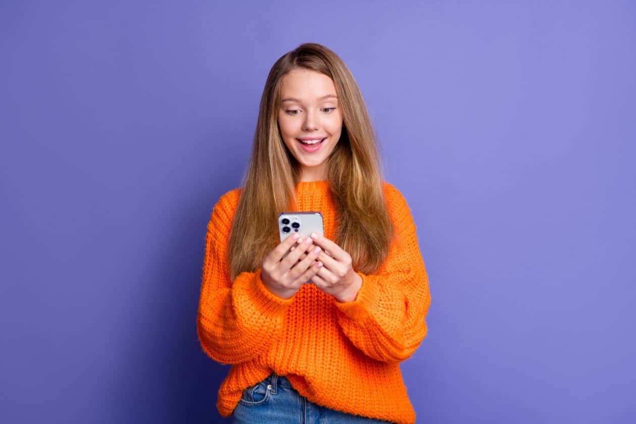 Garota feliz/excitada usando um iPhone 15