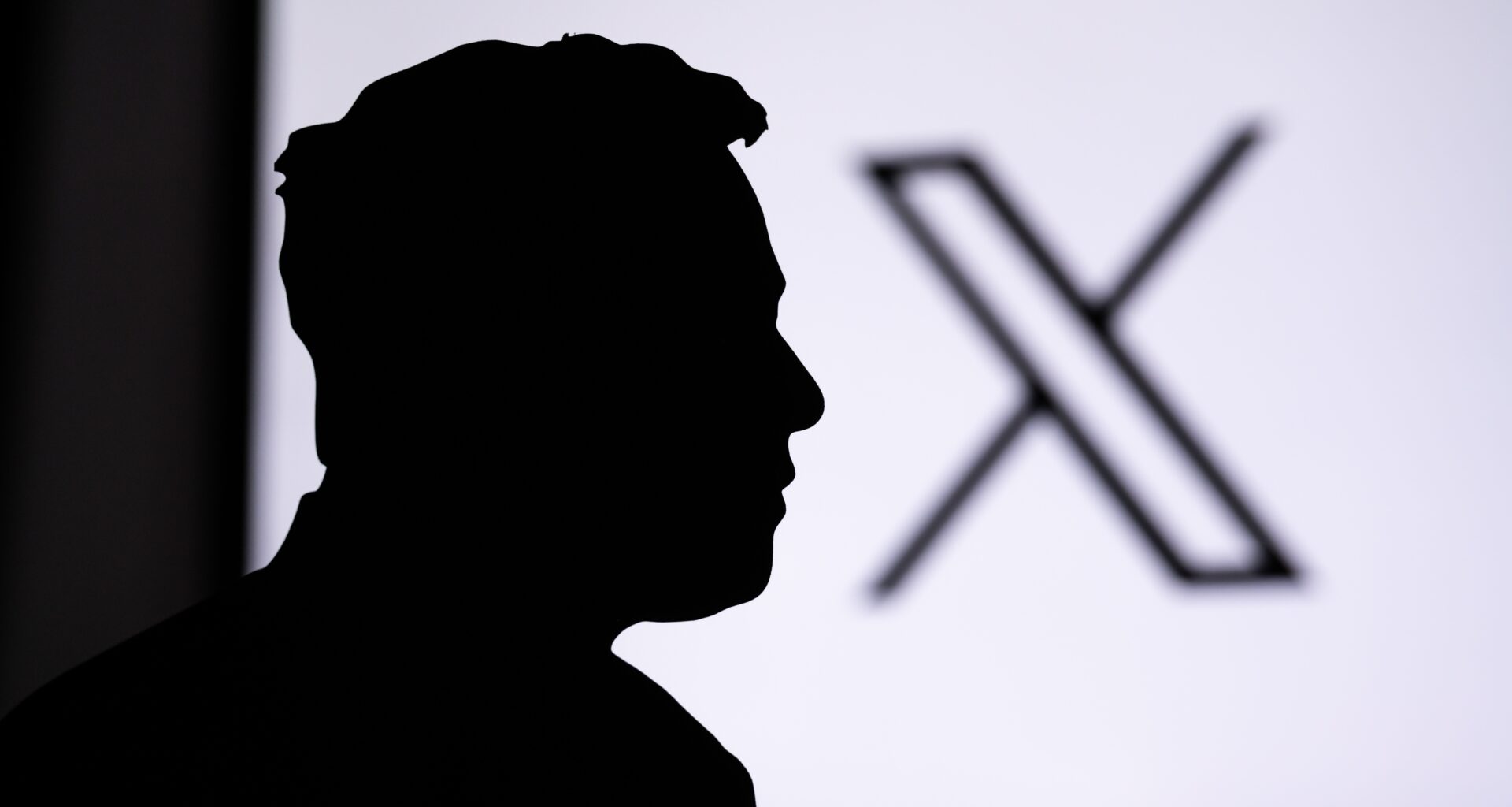 Silhueta de Elon Musk em primeiro plano e o logo do X em segundo plano