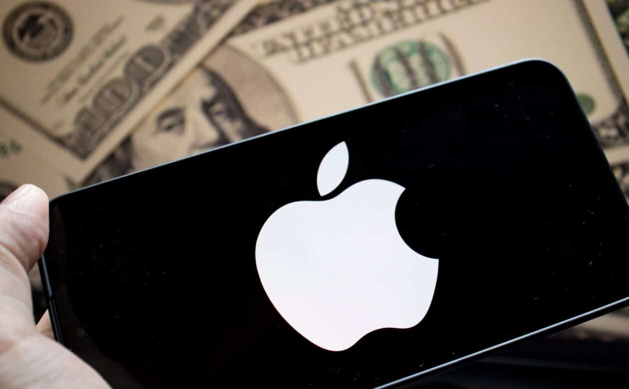 Logo da Apple em um smartphone em frente a notas de dólar