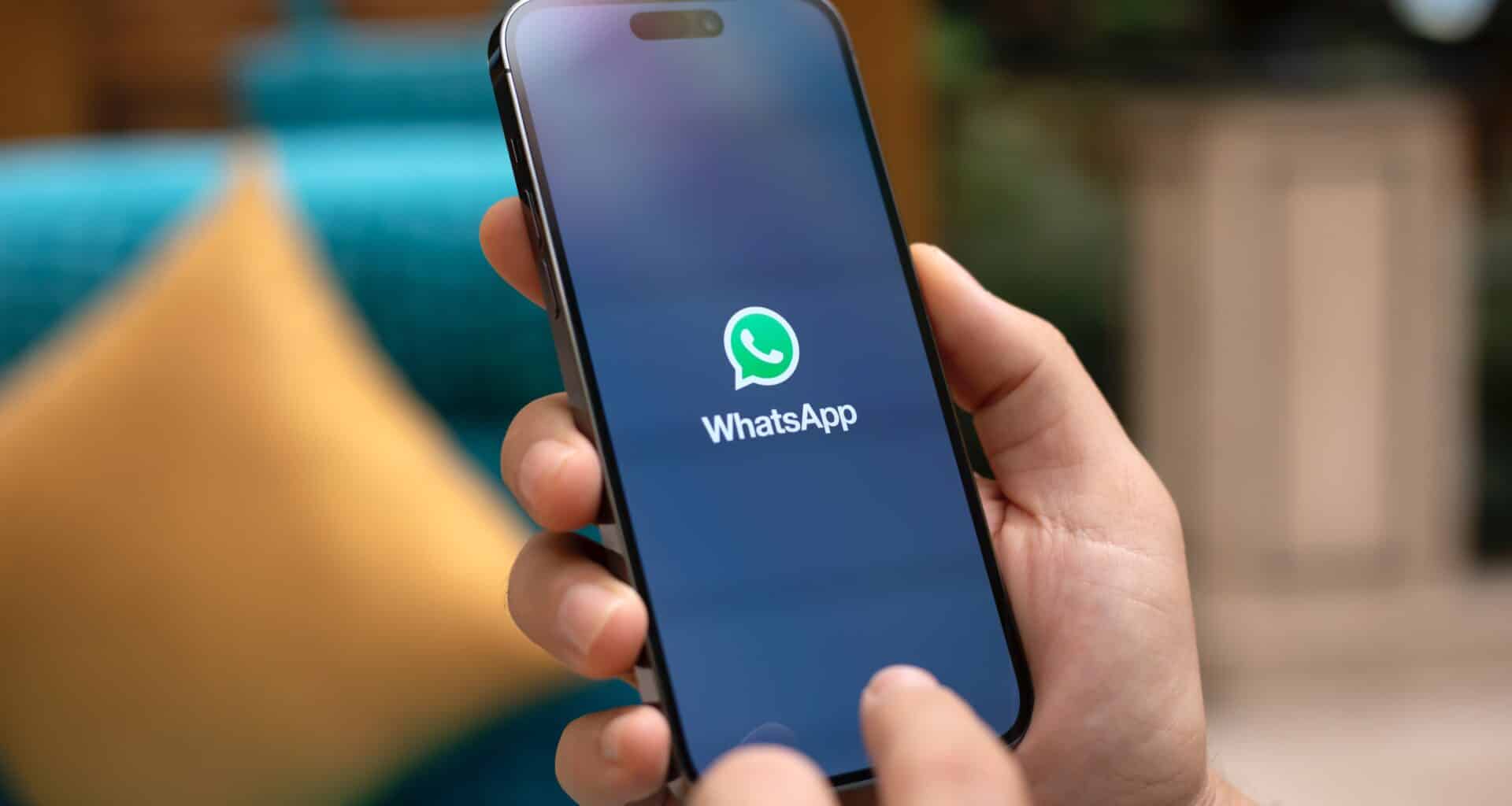 Mão segurando um iPhone 15 Pro Max com o WhatsApp