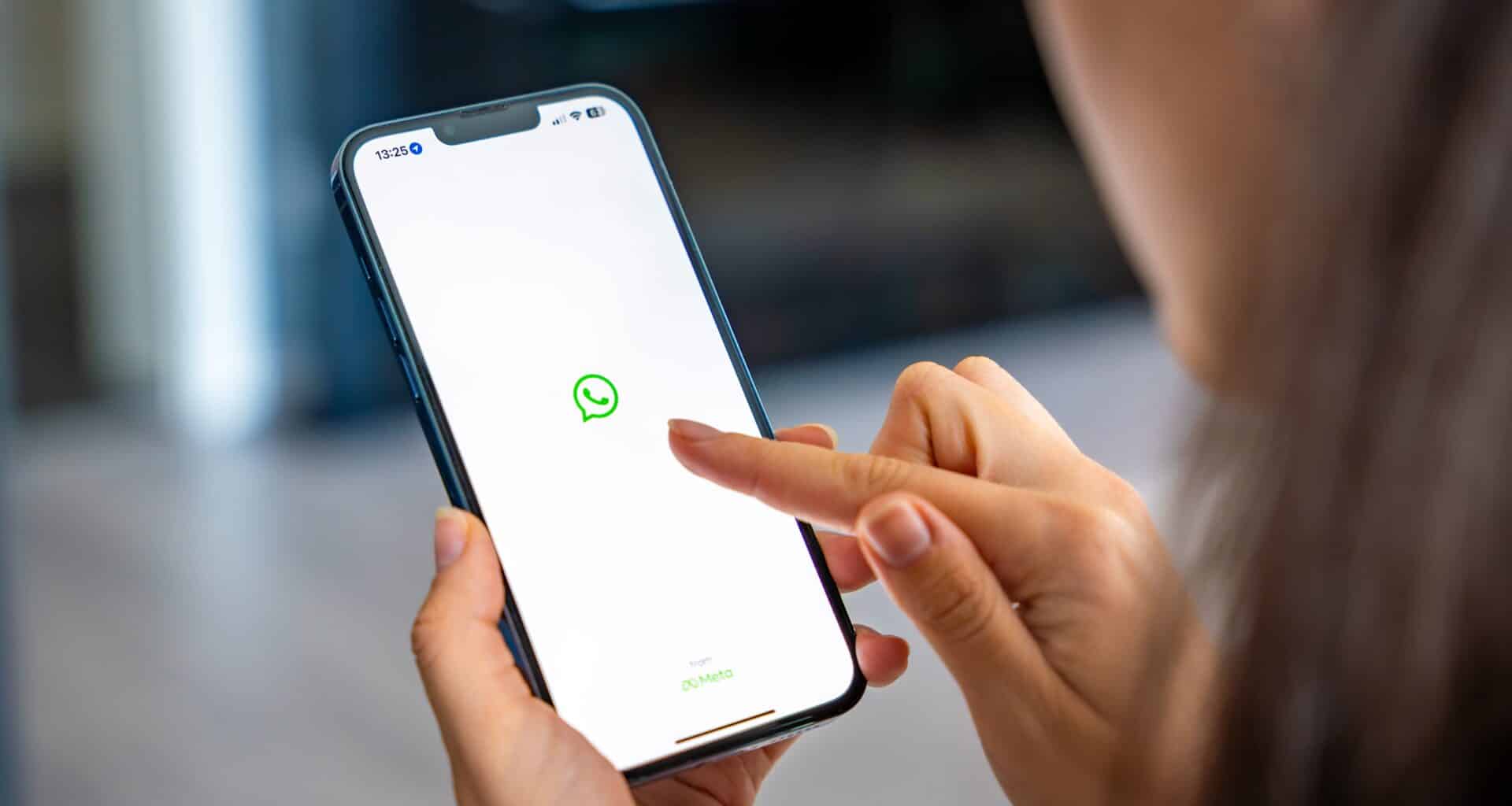 Mulher segurando um iPhone com o aplicativo de bate-papo WhatsApp na tela