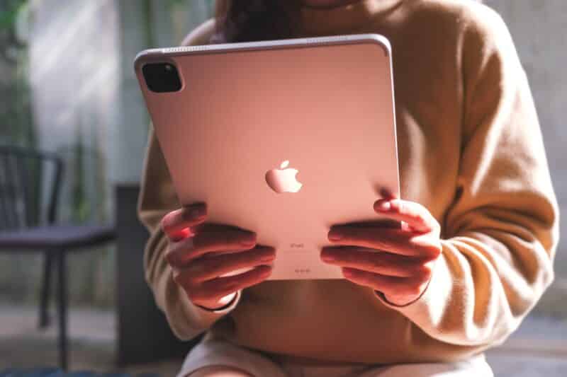 Mulher/menina usando um iPad Pro com reflexo de luz rosa