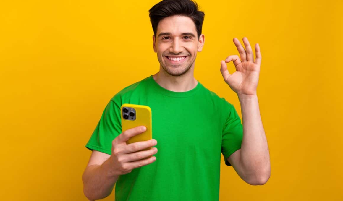 Homem fazendo gesto com um iPhone na mão