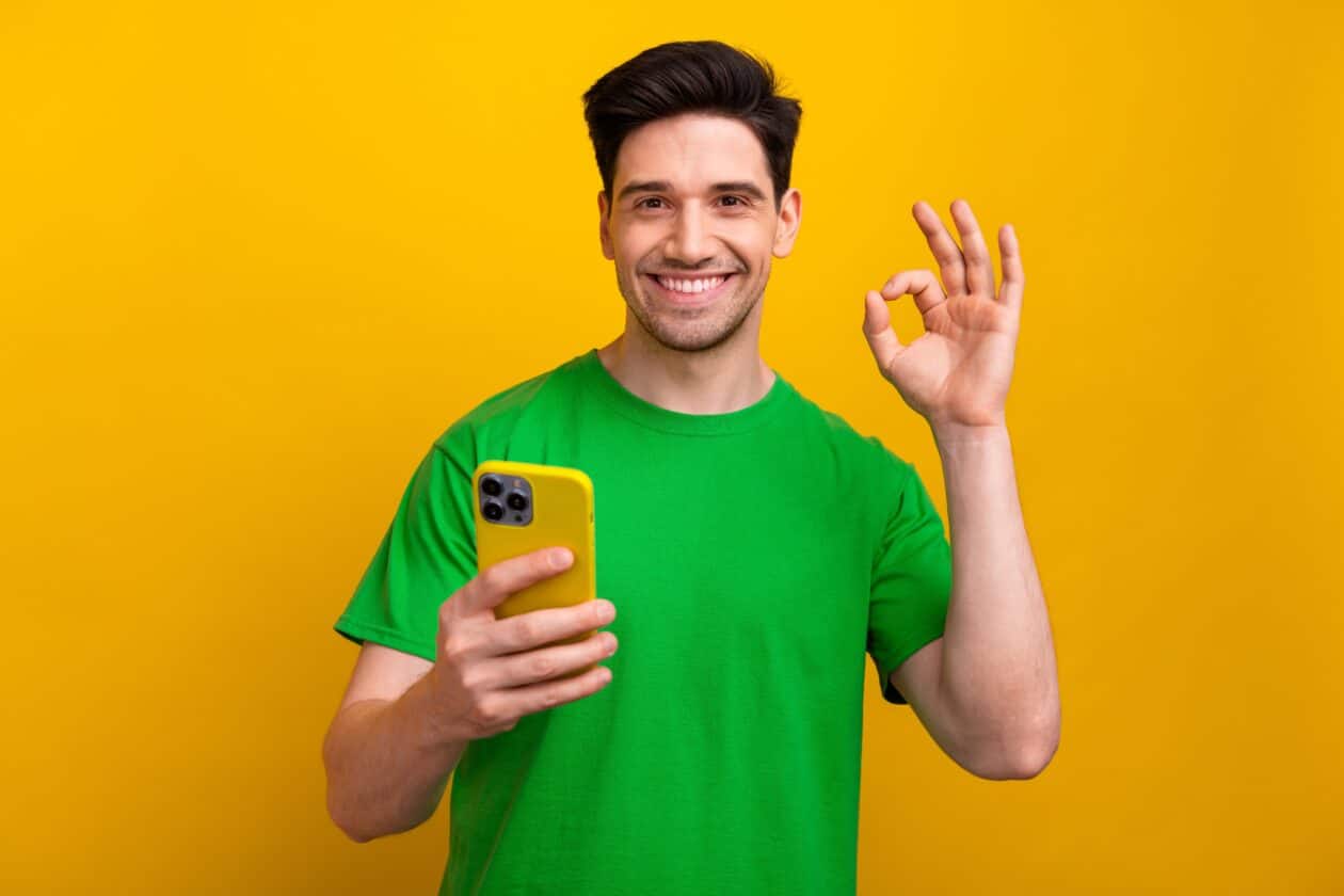 Homem fazendo gesto com um iPhone na mão