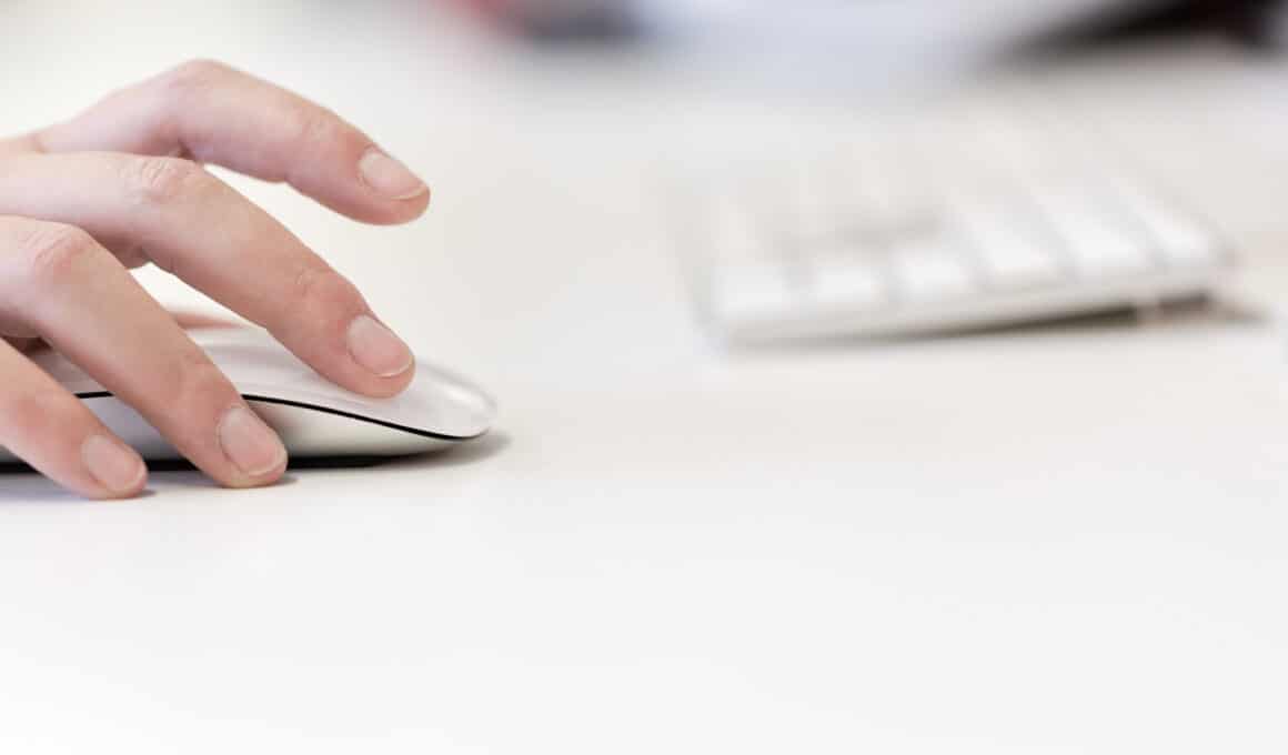 Mulher usando Magic Mouse com teclado desfocado ao fundo