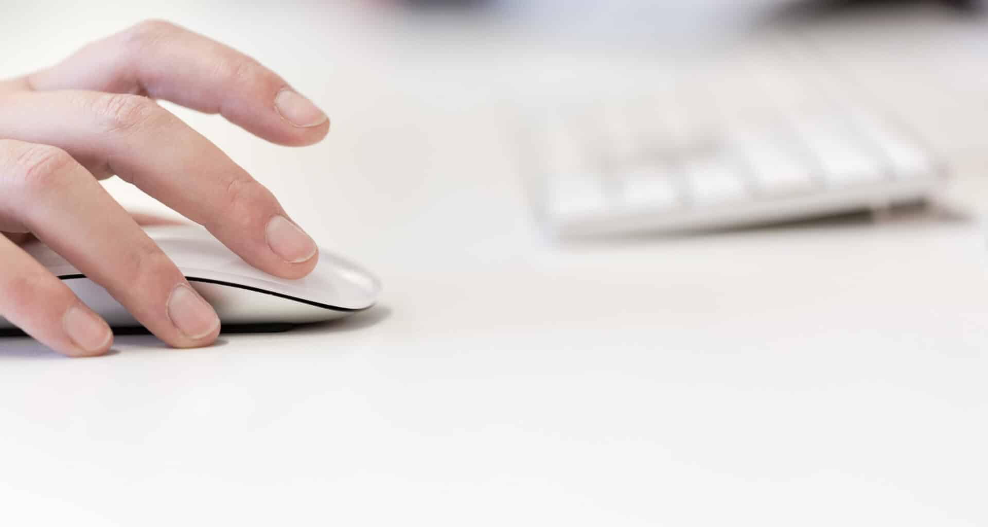 Mulher usando Magic Mouse com teclado desfocado ao fundo