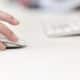 Mulher usando Magic Mouse com teclado desfocado ao fundo