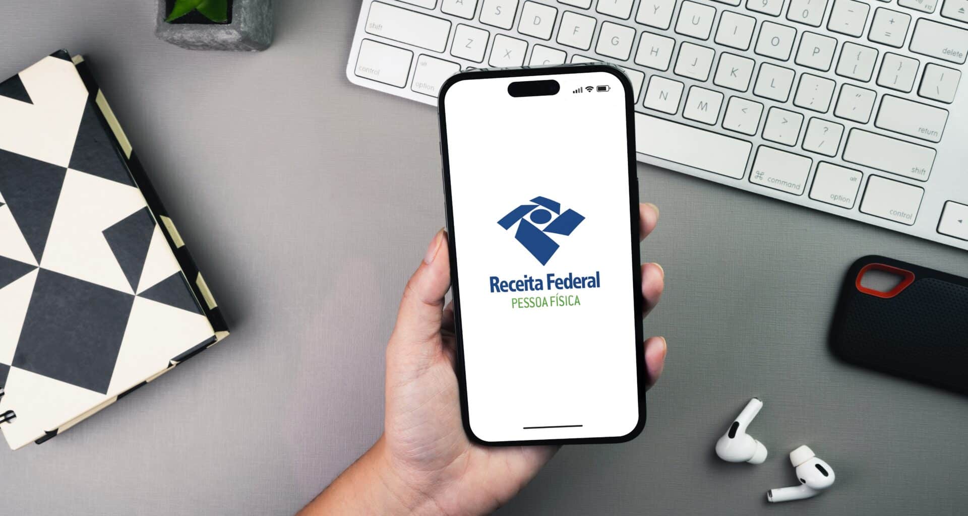 Mão segurando iPhone com Receita Federal/Pessoa Física