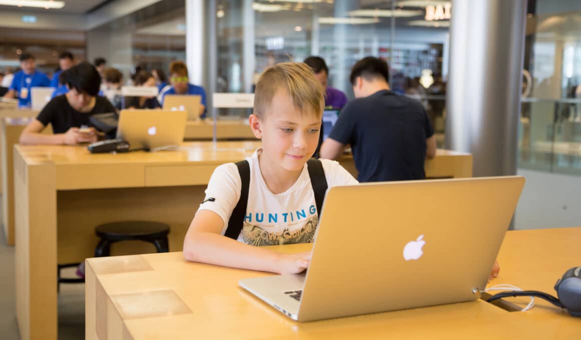 Menino usando MacBook em Apple Store