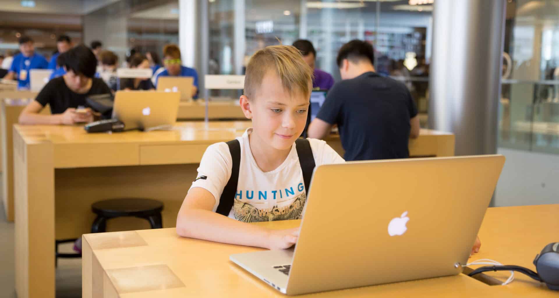 Menino usando MacBook em Apple Store