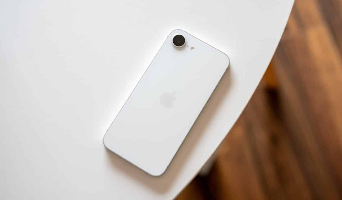 iPhone 16e branco em cima de uma mesa com a tela para baixo