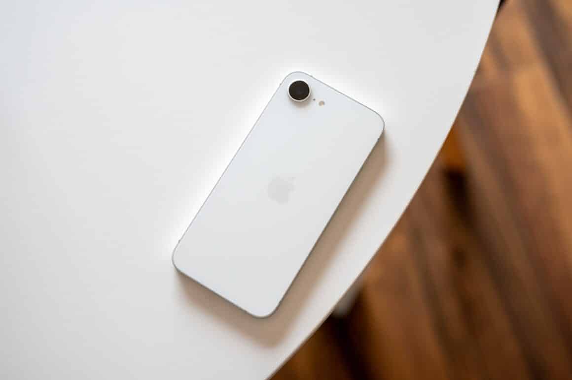 iPhone 16e branco em cima de uma mesa com a tela para baixo