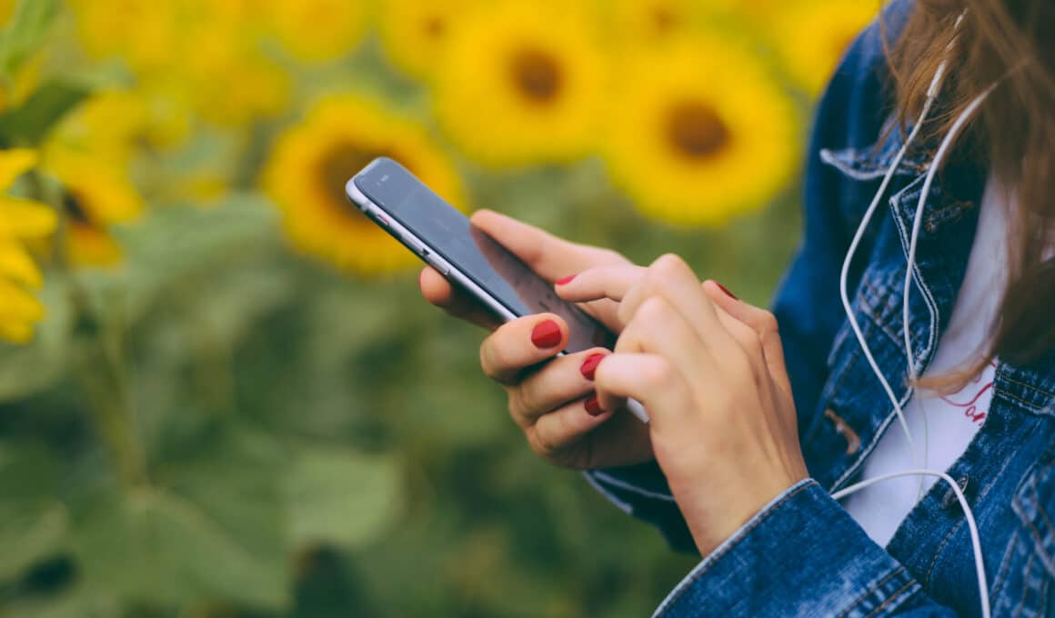 Mulher usando um iPhone com girassóis ao fundo