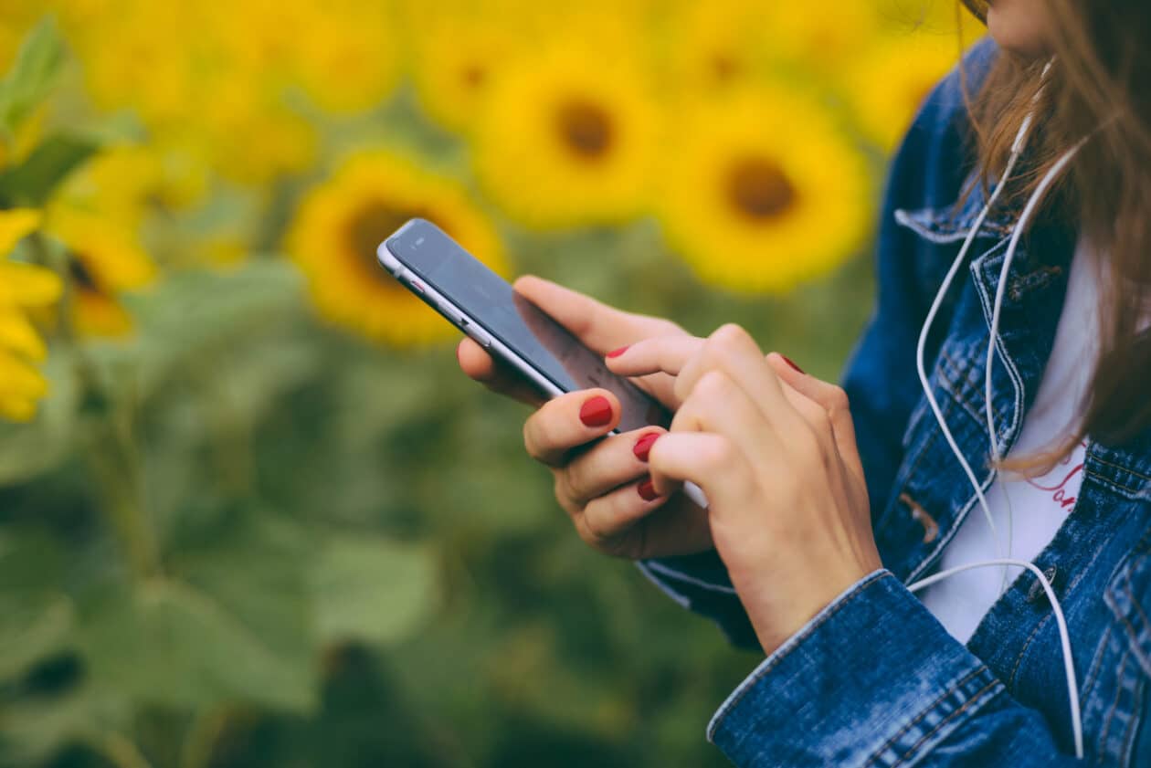 Mulher usando um iPhone com girassóis ao fundo