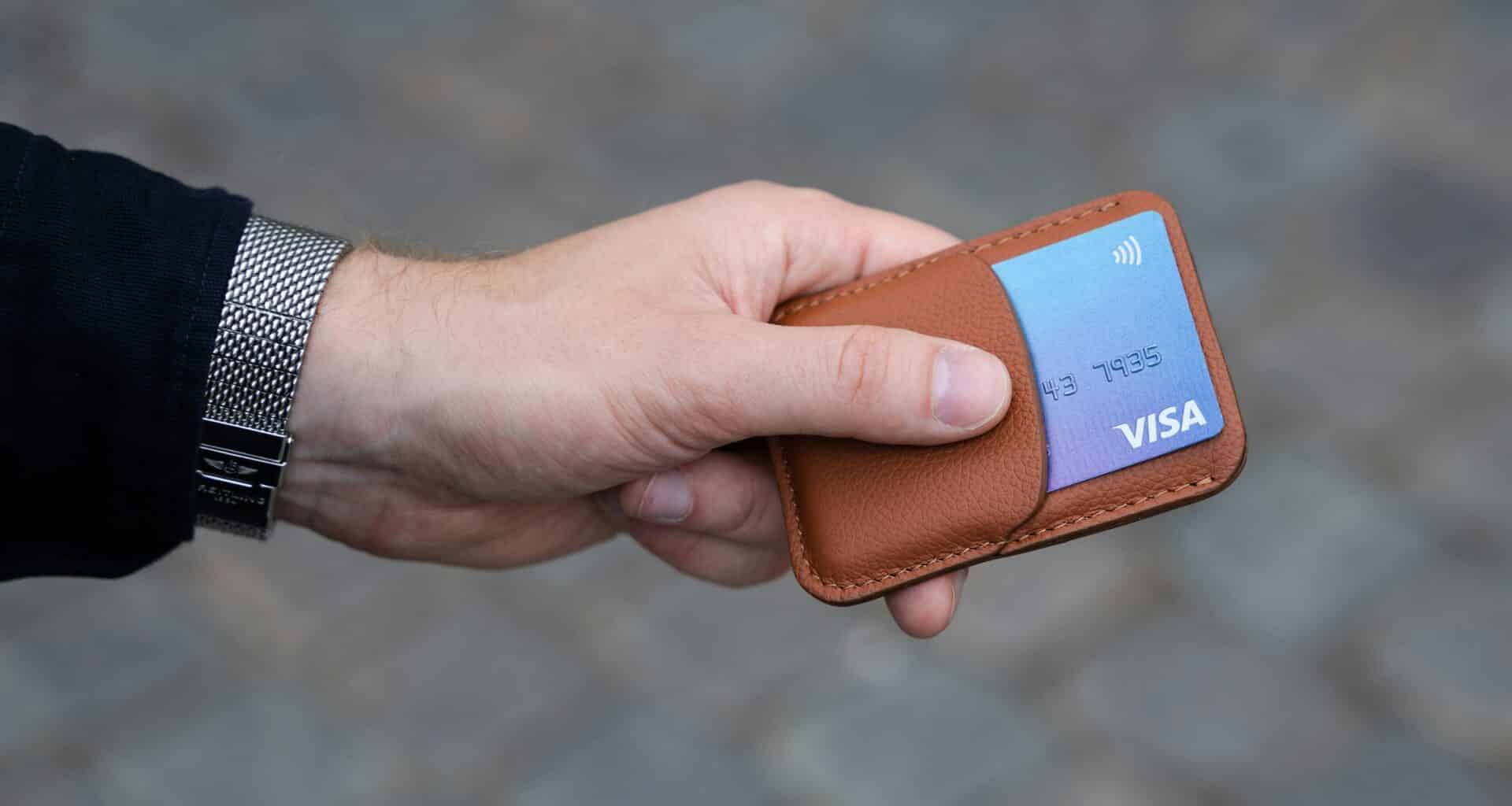Mão segurando uma carteira de iPhone com um cartão de crédito