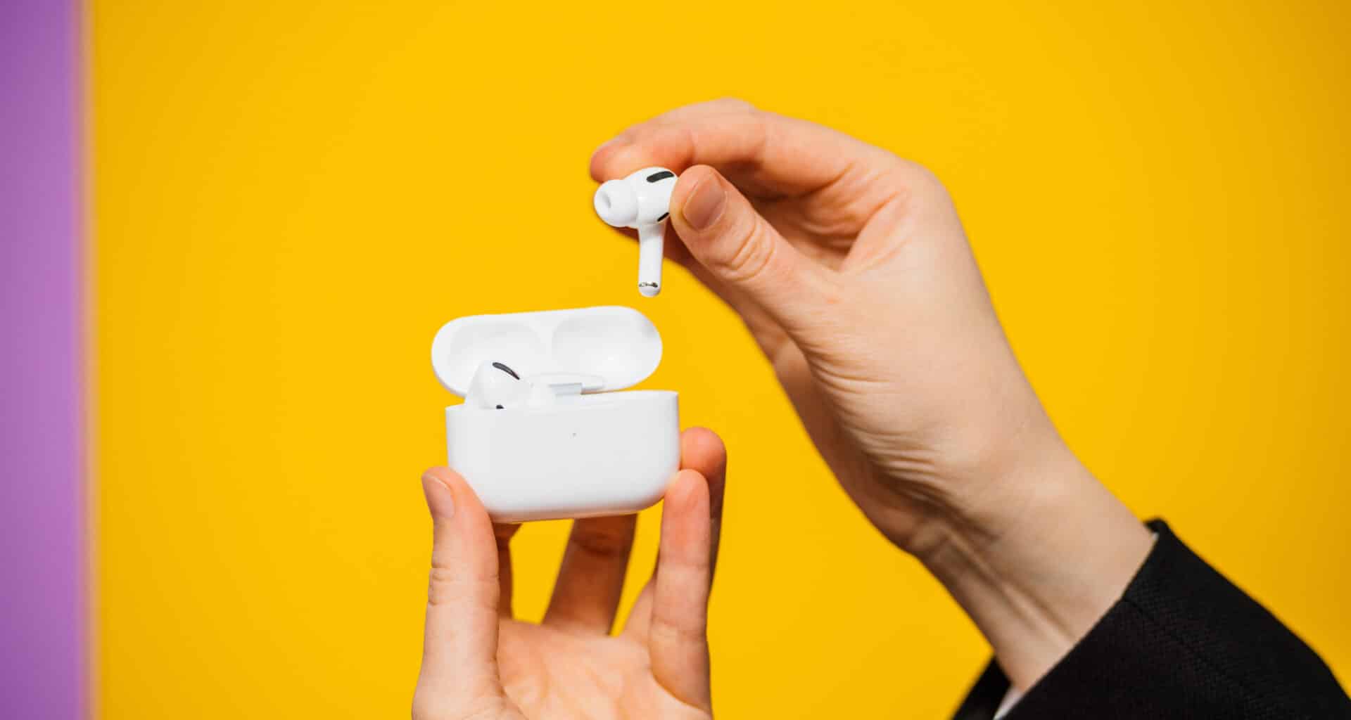 AirPods Pro em mãos sobre fundo amarelo