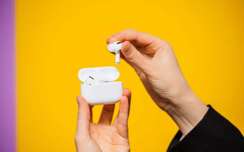 AirPods Pro em mãos sobre fundo amarelo