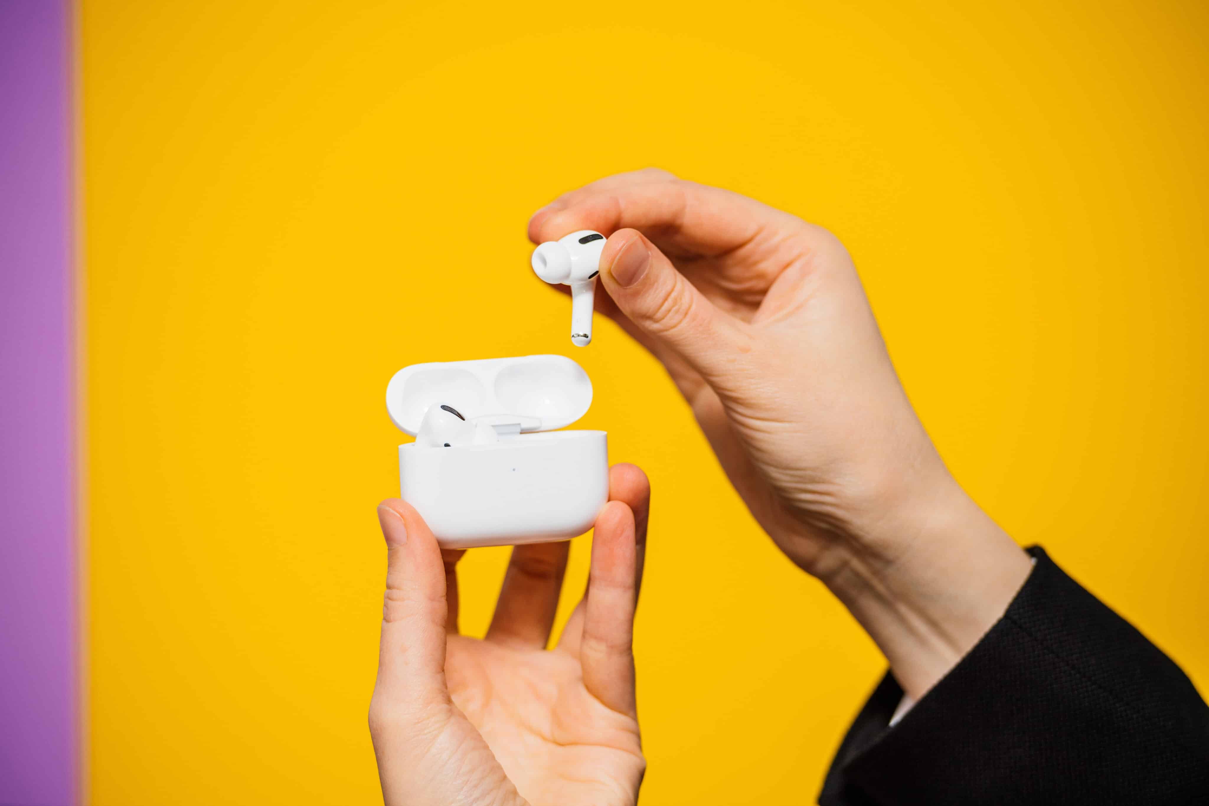 AirPods Pro em mãos sobre fundo amarelo