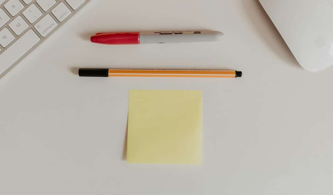 Post-it ao lado de canetas, teclado e mouse