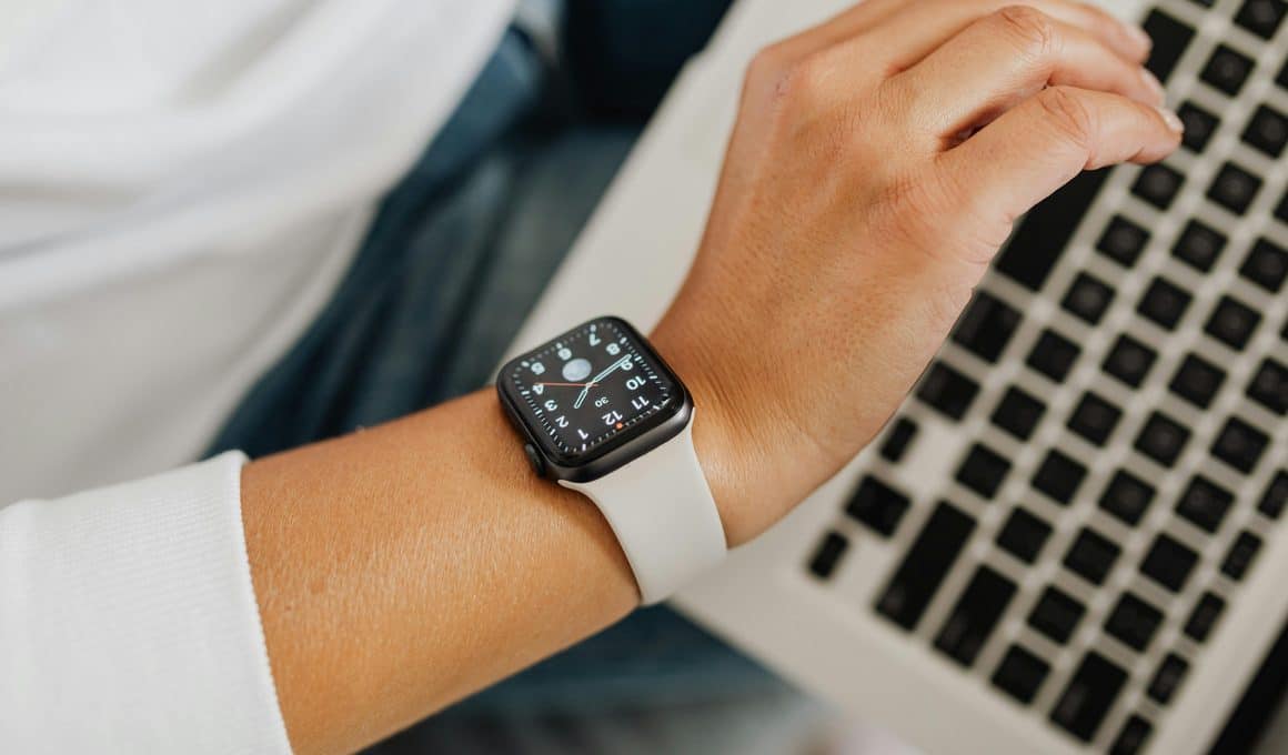 Pessoa olhando para o Apple Watch com um Mac ao fundo