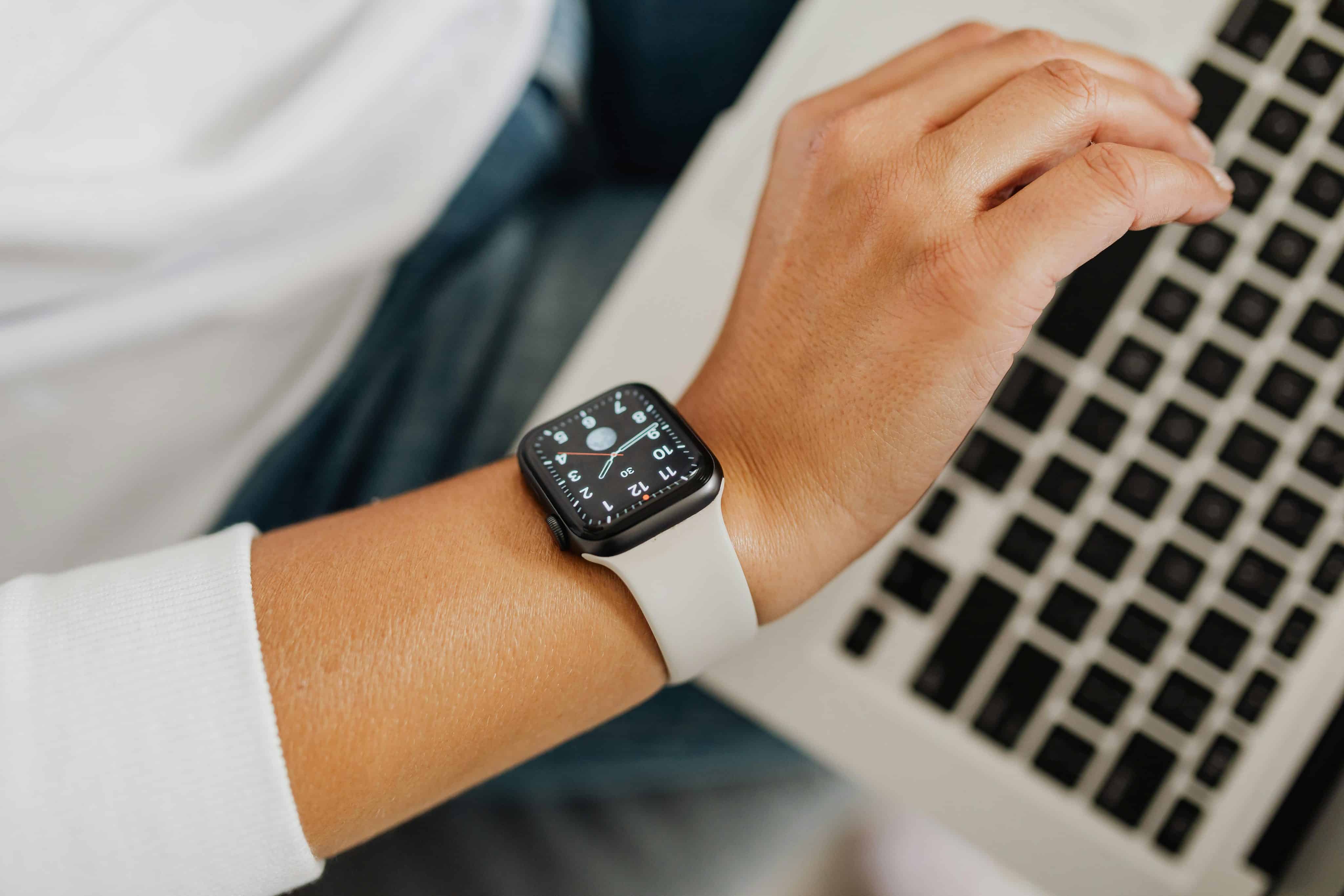 Pessoa olhando para o Apple Watch com um Mac ao fundo