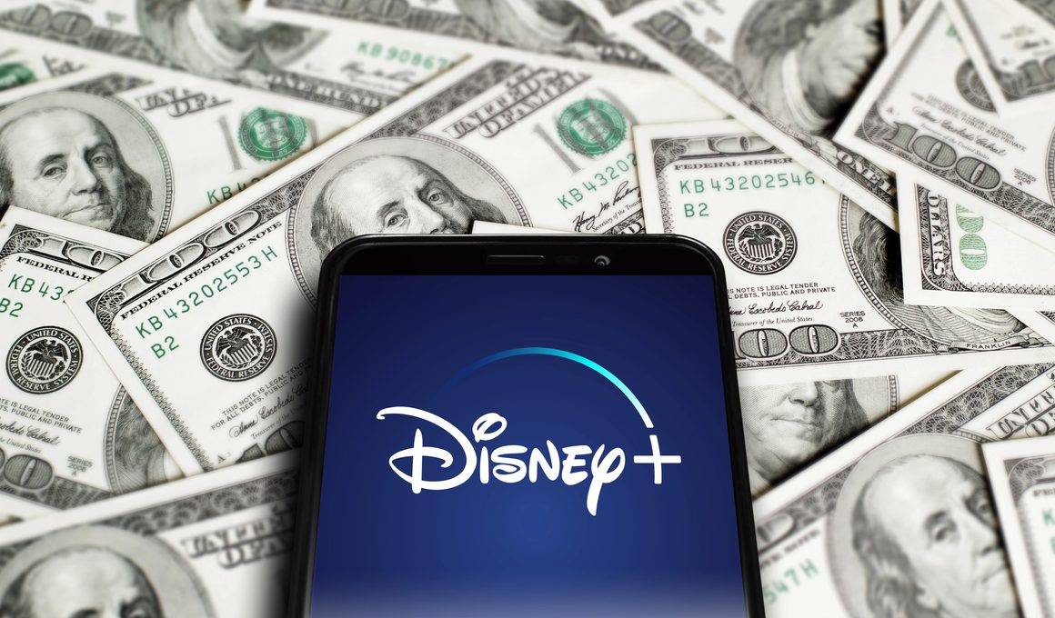 Logo do Disney+ em um telefone em cima de dinheiro (dólares)