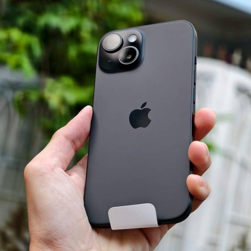 Mão segurando um iPhone 15 preto