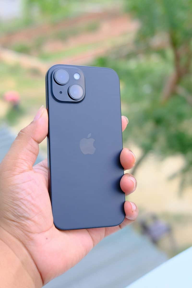 Mão segurando um iPhone 15 preto