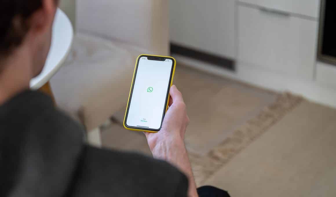 Homem segurando um iPhone com o logo do WhatsApp