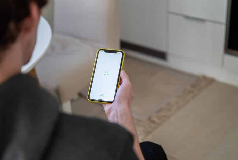 Homem segurando um iPhone com o logo do WhatsApp