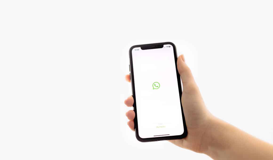 Mão segurando um iPhone com o logo do WhatsApp