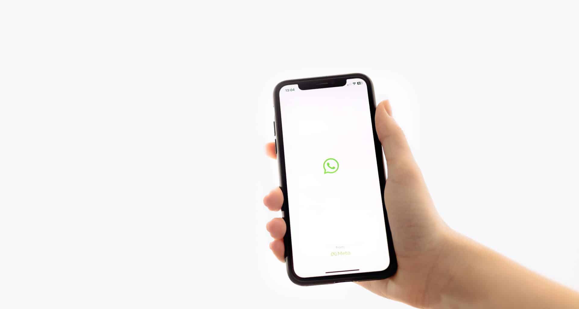 Mão segurando um iPhone com o logo do WhatsApp
