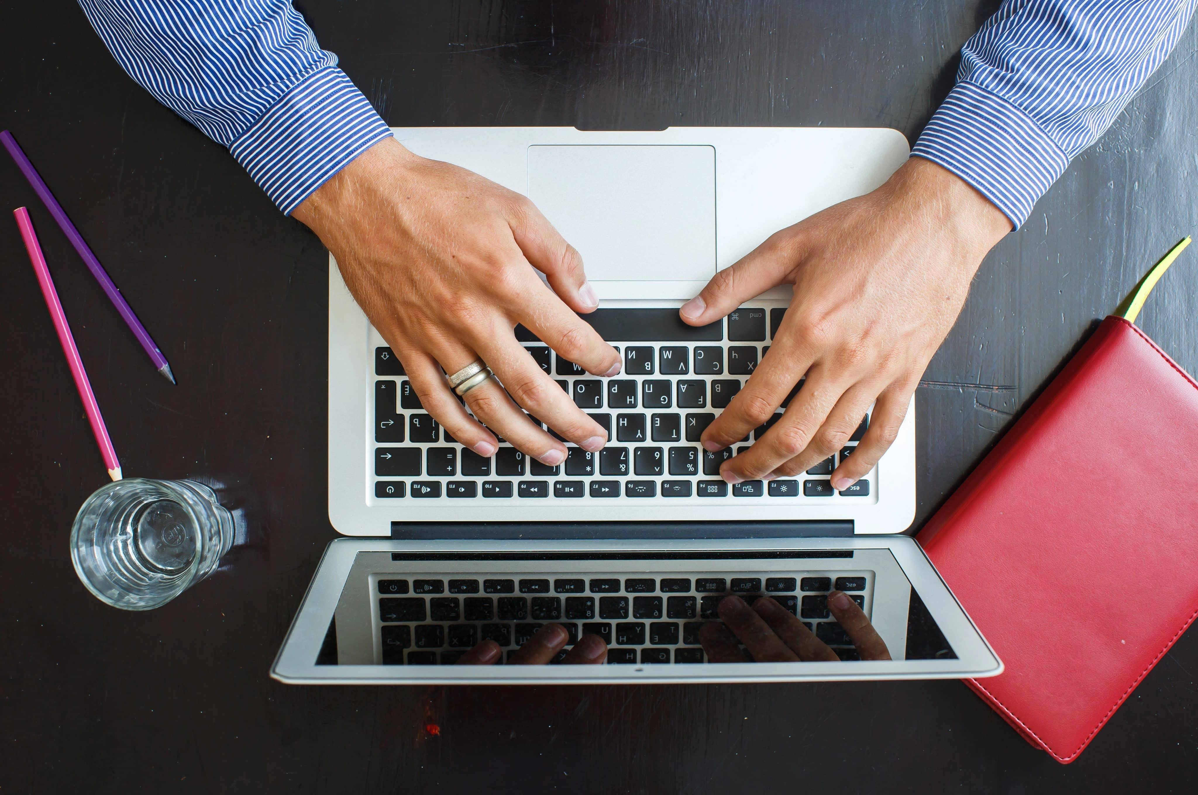 Homem trabalhando/digitando em MacBook
