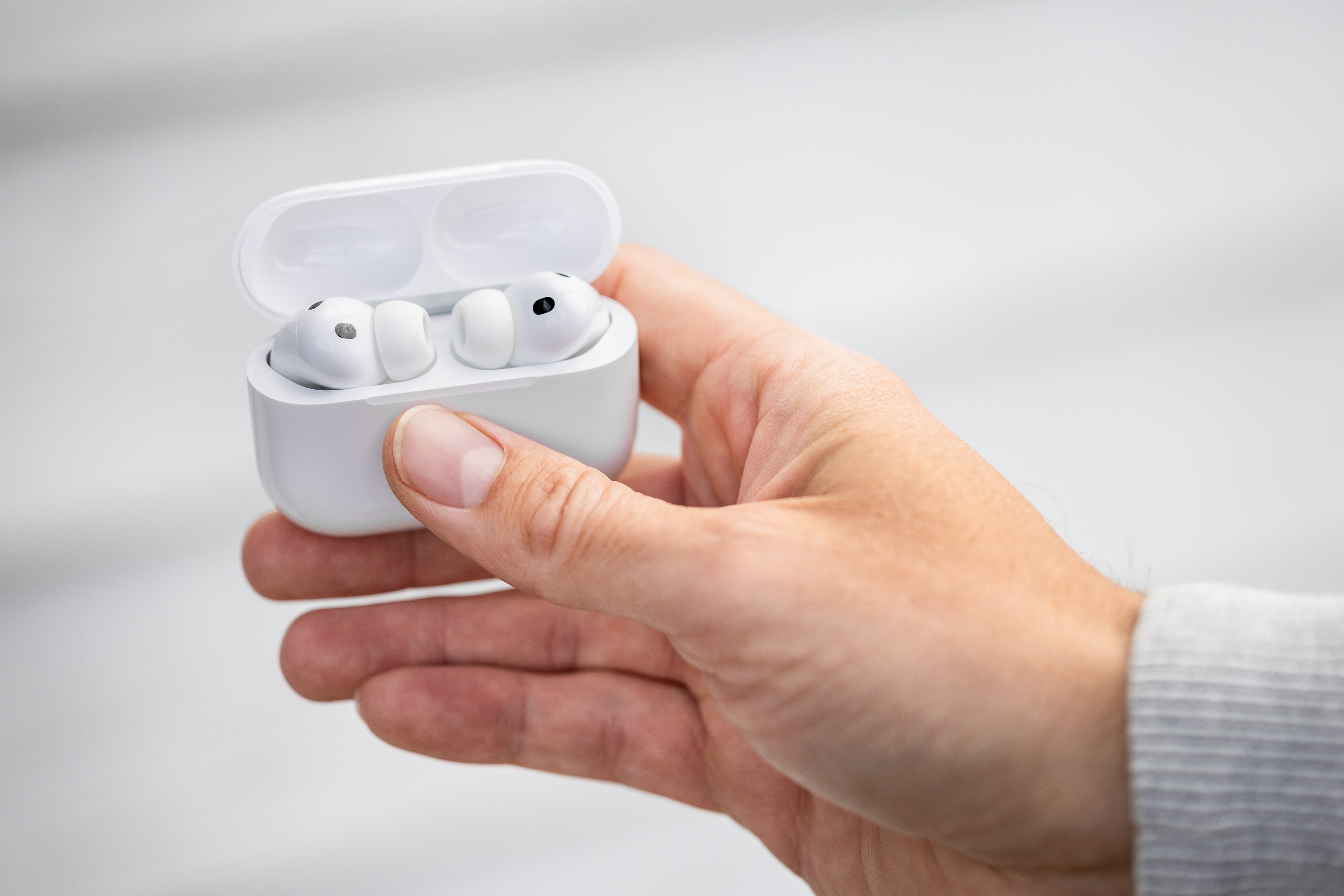 Mão segurando a case dos AirPods Pro 3 aberta com os fones aparecendo
